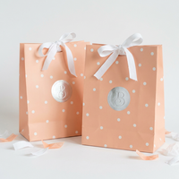 Sacs en papier d'art de luxe pour robes, blancs avec impression géométrique, laminage, nœud en satin argenté et poignées torsadées