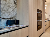 Meuble de cuisine moderne de luxe en bois clair sur mesure avec porte à panneau plat, îlot cascade en marbre et crédence pour villa