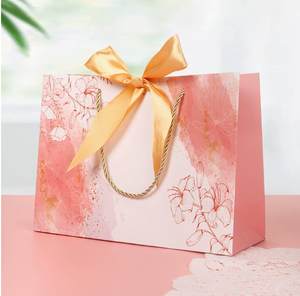 ถุงกระดาษคราฟท์ลายดอกไม้สีชมพูพิมพ์โลโก้ตามสั่ง สำหรับใส่ของชำ ของขวัญ บรรจุภัณฑ์ พร้อมหูหิ้วและริบบิ้นสีทอง - Product Image 1