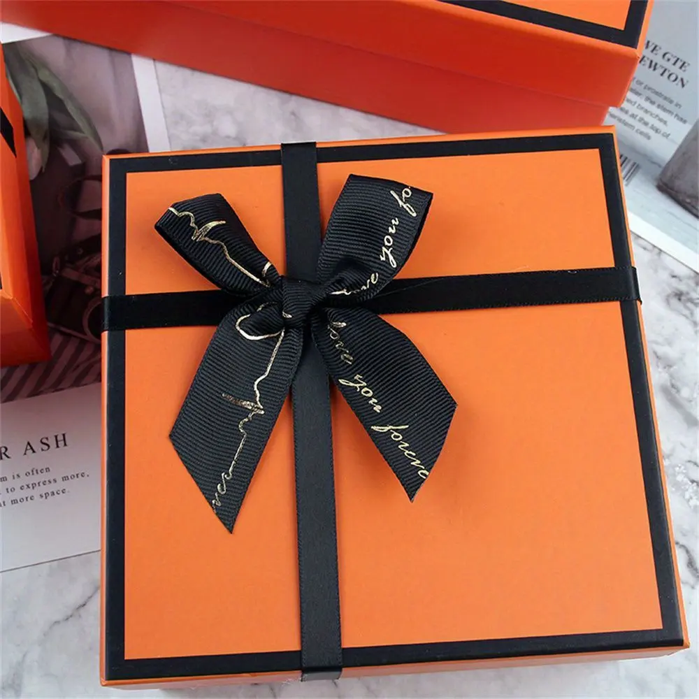 कस्टम उपहार उत्पाद बॉक्स पैकेज नारंगी ढक्कन हार्ड खाली कार्डबोर्ड उपहार बॉक्स कटा हुआ पेपर फिलर ब्लैक रिबन के साथ