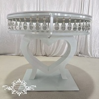 Table de mariage blanche avec cadre en forme de cœur orné de gouttes de cristal et plateau rond en acier inoxydable