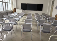Chaise pliante de conférence grise avec tablette d'écriture, siège rembourré et accoudoirs, pour la formation et les réunions en salle de classe, fournie directement par l'usine