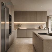 Meubles de cuisine en laque mate gris-beige, style luxe discret, avec unités murales rainurées verticalement et îlot sans poignées, pour maison de luxe