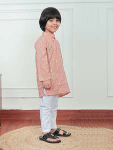 Lindo niño pequeño con kurta color melocotón con estampado colorido y pijama blanco, sonriendo en el interior con un atuendo festivo tradicional. - Product Image 3