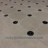 Carrelage de sol en pierre calcaire beige avec points noirs en forme d'échiquier