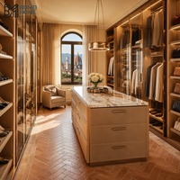 Dressing sur mesure italien beige chaud avec armoires en verre et finitions or rose, et îlot de rangement de luxe en marbre