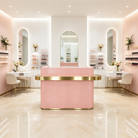 Comptoir de réception rose sur mesure haut de gamme avec panneau à rayures minimalistes et décoration dorée pour salon, spa, centre de beauté et bien-être