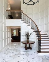Escalier courbé en marbre et bois massif avec balustrade en fer forgé ornée, sur mesure pour villa européenne de luxe