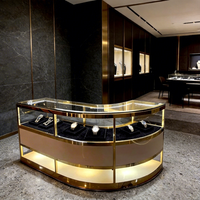 Ensemble de présentoirs de bijouterie moderne avec cadre doré, écoresponsable, éclairage LED, îlot central incurvé et vitrines périmétriques pour la vente au détail de luxe