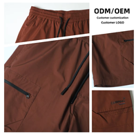 Short cargo zippé pour homme marron, taille élastique, cordon de serrage noir, poches latérales zippées, poche arrière à rabat, longueur genou avec détail cordon à extrémité.