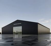 Entrepôt industriel préfabriqué en structure acier avec revêtement métallique foncé et entrée à pignon vitré