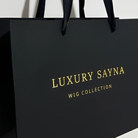 Sacs shopping en papier noir mat élégants avec logo personnalisé, impression dorée à chaud, et poignées en ruban pour l'emballage de perruques en boutique