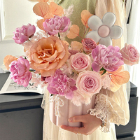Arrangement floral tridimensionnel mignon de style coréen, avec un joli seau à collation et des petites boîtes en papier rondes, pour une composition florale artistique et une ambiance douillette