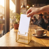 Présentoir minimaliste en fil doré avec base ouverte pour brochures, cartes et petites impressions d'art sur comptoir