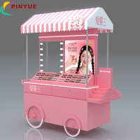 Chariot de présentation mobile haut de gamme rose personnalisé pour cosmétiques et parfums, avec auvent et roues, idéal pour les événements en centre commercial