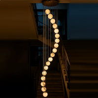 Lustre moderne en spirale pour escalier long, avec boules en albâtre naturel et structure métallique, idéal pour villa et hall à plafond haut