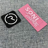 Nouvelle version d'étiquette tissée en damassé beige gaufré avec logo en silicone 3D découpé au laser pour l'impression sérigraphique sur vêtements