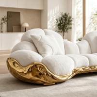 Canapé multiplace incurvé en bouclette blanche avec base en fibre de verre sculptée dorée et table basse ronde en pierre pour salon de luxe