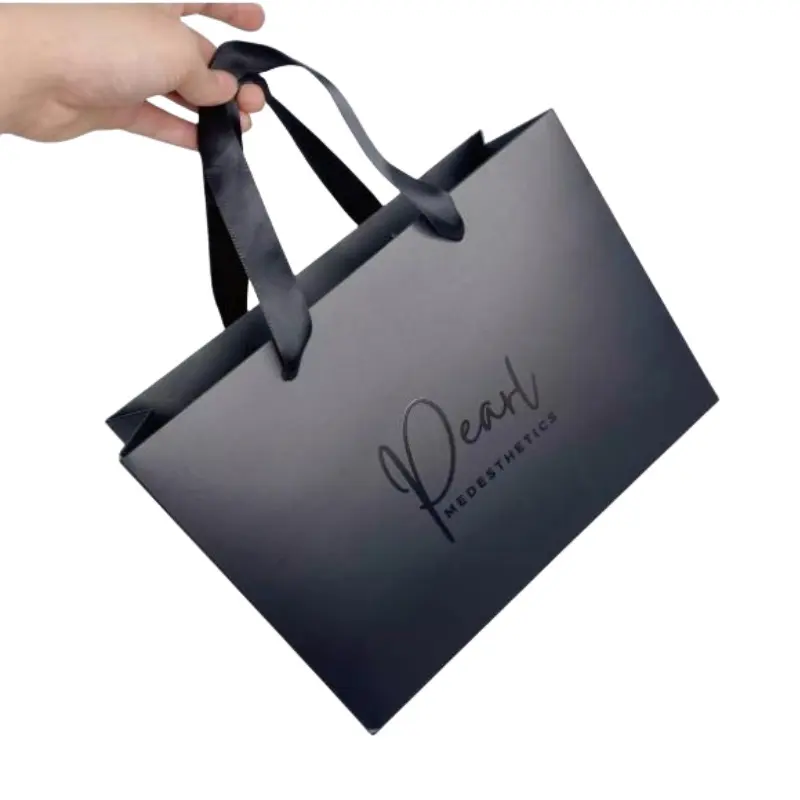 Vente en gros de sacs à provisions de cadeau en papier de luxe imprimés personnalisés en noir avec poignée et nœud, sacs en papier de luxe avec votre propre logo
