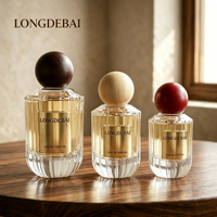 Venta al por mayor en stock: Botella de perfume de vidrio transparente con rayas verticales cilíndricas de 30ml, 50ml, 100ml, botella de perfume vacía con tapa de bola de madera.