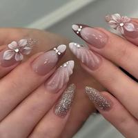 Faux ongles press-on en acrylique faits main, couleur nude amande, avec fleurs blanches 3D, dégradé de paillettes et décoration en strass queue de poisson