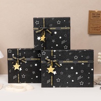 Boîte cadeau rigide à deux pièces noire avec logo personnalisé, impression étoile, paillettes, couvercle et base, avec ruban imprimé et pendentif étoile pour les fêtes