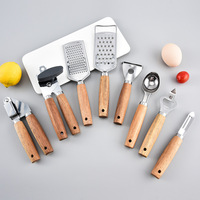 Ensemble d'ustensiles de cuisine en acier inoxydable avec manche en bois : râpe, ouvre-boîte, couteau à pizza, outils de cuisson, de découpe et de service