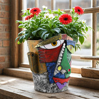 Pot de fleurs en résine avec visage abstrait coloré et fleurs roses pour décoration intérieure