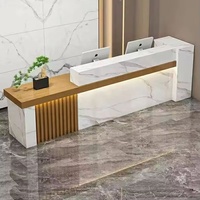 Bureau d'accueil moderne avec panneau frontal aspect marbre, accent en lattes de bois et deux postes de travail