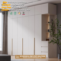 Armoire complète moderne et minimaliste blanche avec portes sans poignées et éclairage LED, menuiserie sur mesure pour les constructeurs de maisons aux États-Unis