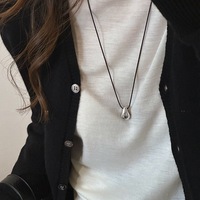 Collier long en alliage bicolore or et argent avec pendentif goutte d'eau et cordon en cuir noir pour femme, idéal pour un style décontracté, urbain ou quotidien, parfait comme cadeau.