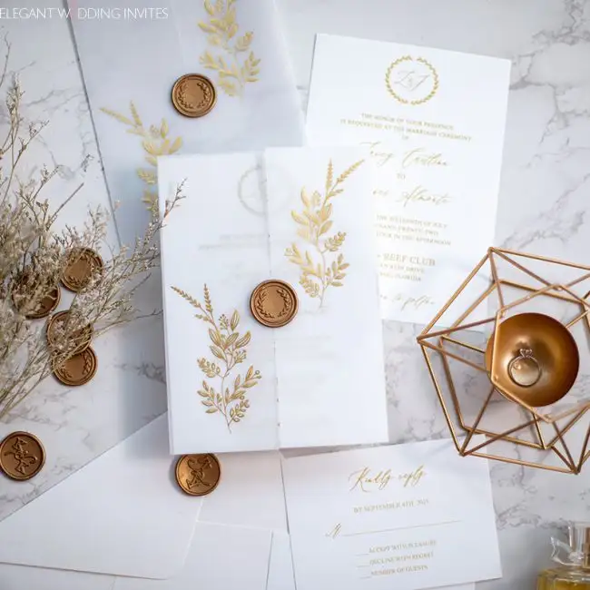 دعوة زفاف بتصميم بسيط من ورق القصدير الذهبي مُزينة بأوراق شجر رقيقة مع ختم شمعي