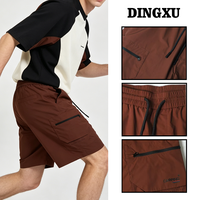 Short cargo zippé pour homme marron, taille élastique, cordon de serrage noir, poches latérales zippées, poche arrière à rabat, longueur genou avec détail cordon à extrémité.