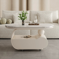 Table basse mobile incurvée en crème, surface en pierre microcristalline, base de rangement avec roulettes silencieuses, bureau minimaliste pour salon
