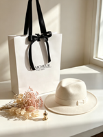 Sac cadeau artisanal en papier biodégradable éco-responsable minimaliste avec logo personnalisé et nœud en ruban satiné noir pour boutique de mode et magasin de chapeaux