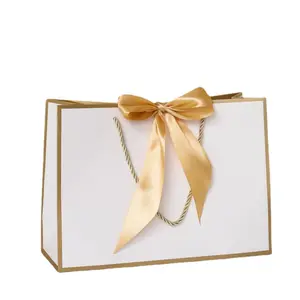 Sacchetto della spesa di carta bianca personalizzato di lusso che spedisce i sacchetti della stampa del bollettino con il logo dell'oro per i vestiti dei regali compongono l'imballaggio con il nastro