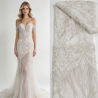 Tissu en dentelle de haute couture lourdement perlé avec franges en boucle motif feuille d'argent sur tulle ivoire pour robe de mariée et robe de soirée