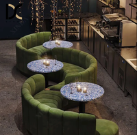 Canapé banquette capitonné en velours vert à cannelures courbes, table ronde à plateau en terrazzo bleu pour restaurant, bar à vin ou lounge aux tons sombres