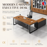 Bureau de direction en forme de L avec plateau en bois grainé, structure en métal noir mat et panneau de modestie