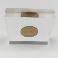 Pièce de monnaie en laiton incrustée dans un bloc acrylique transparent sur support de présentation – Décoration de bureau style vintage, objet de collection, presse-papiers
