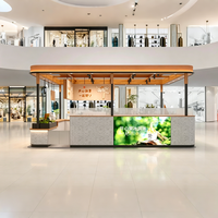 Kiosque de vente en bois chaud et pierre patinée avec éclairage LED, design écologique, proposant des glaces à la pistache