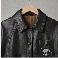 Veste en cuir noire style vintage américain, col à revers, boutons noirs simples, broderie monstre avec ligne fendue incurvée, coupe courte ample