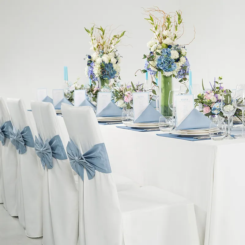 ผ้าคลุมเก้าอี้สีฟ้าและสีขาวพร้อมท่อผ้าคลุมโต๊ะในโรงแรมผ้าคลุมเก้าอี้สำหรับงานเลี้ยงงานแต่งงาน
