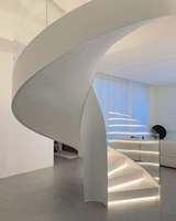 Design d'escalier courbé élégant avec balustrade en verre sans joint et système d'éclairage intégré pour la rénovation intérieure de maisons de luxe