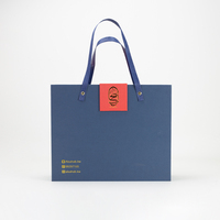 Boîte cadeau de Noël et du Nouvel An bleue, orange et rouge en papier couché avec pelliculage brillant et mat, gaufrage et estampage pour bougies