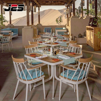 Ensemble de mobilier de patio J2S en métal et bois avec coussin et table, idéal pour les restaurants commerciaux modernes en extérieur et les stations balnéaires.