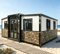 Maison de plage modulaire préfabriquée, extérieur blanc, base en pierre, structure noire, maison de vacances en bord de mer, villa en bord de mer, installation rapide