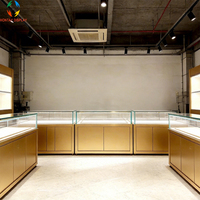 Vitrine à bijoux en verre trempé avec cadre doré brossé et éclairage LED pour magasin de détail haut de gamme, centre commercial de luxe, design écologique