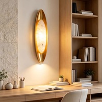 Applique murale moderne de luxe en albâtre avec cadre en métal doré brossé et abat-jour ovale en pierre pour projets hôteliers, chambres et couloirs