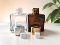 Flacon diffuseur de parfum carré de luxe de 50 ml, disponible en transparent et ambre, avec bouchons et bouchons intérieurs dorés et argentés.